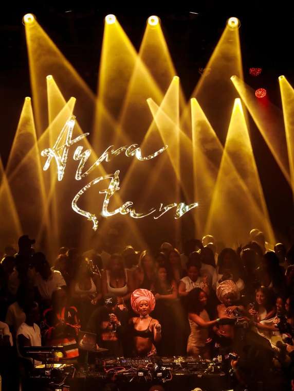Ayra Starr performing on stage wearing a coral headwrap styled by Gele Glamzzz