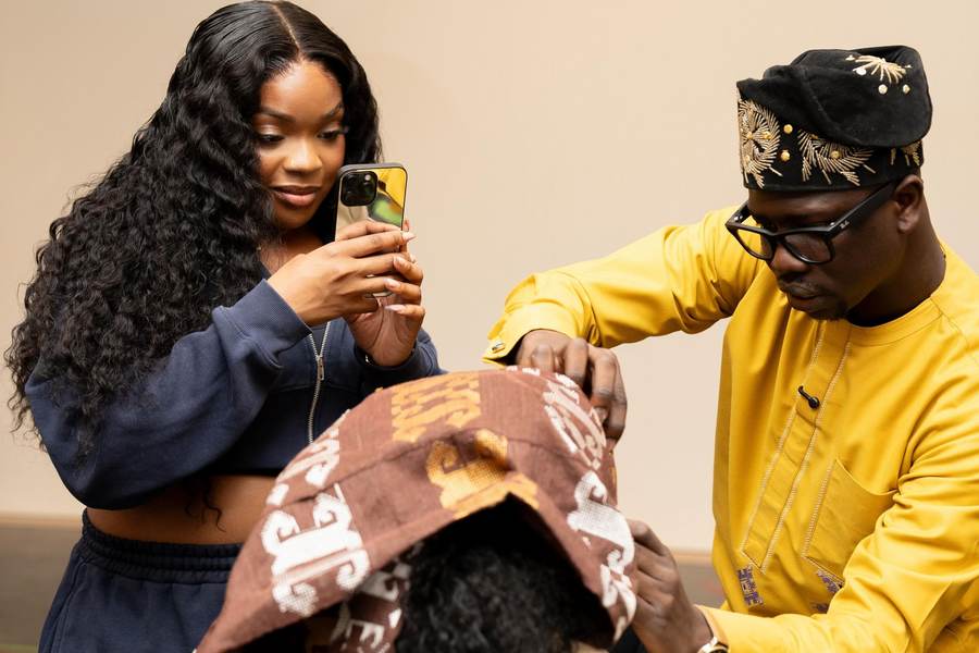 Founder of Gele Glamzzz working closely with fabric during a styling session